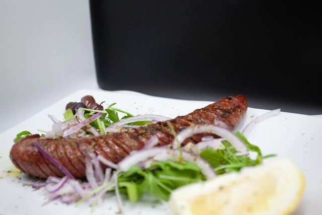 Grilled Greek sausage with arugula, onion and lemon
