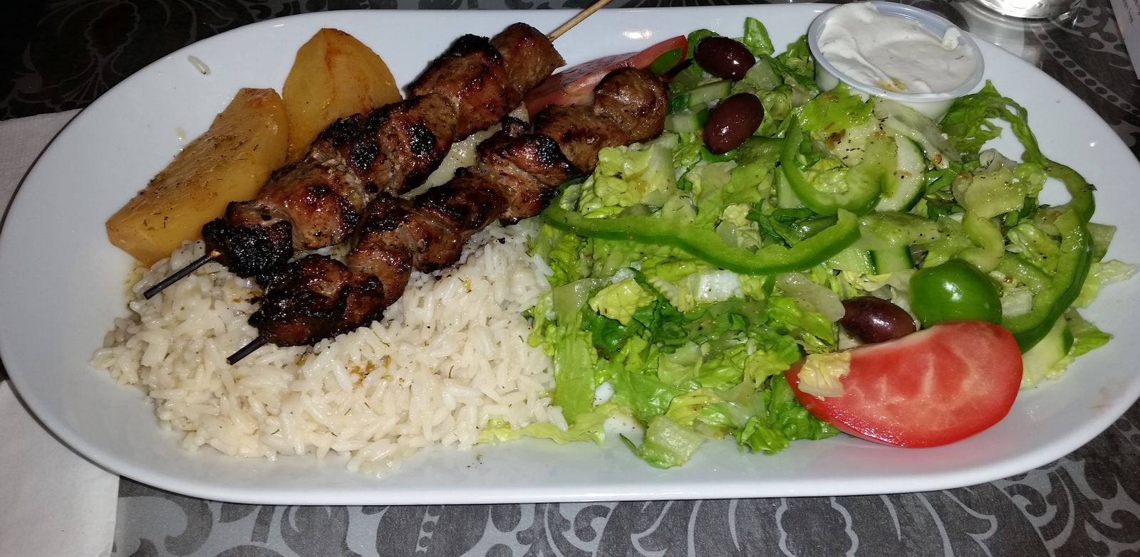 Pork souvlaki skewers with rice, potatoes and salad